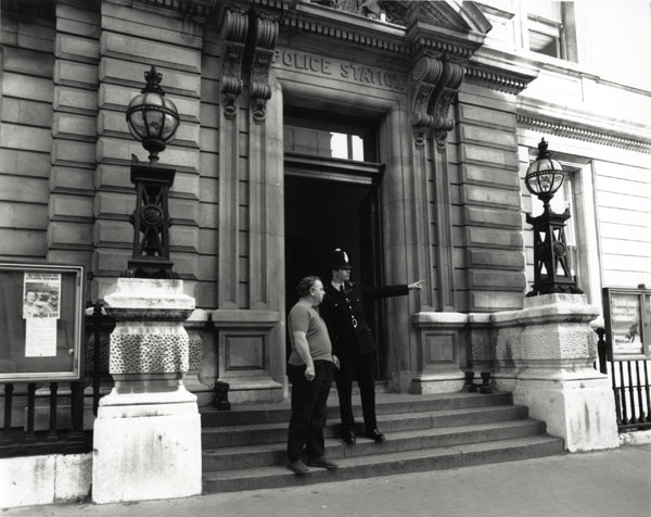 photograph of policeman on steps of Bow Street Police Station giving directions.