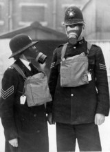 A Police Sergeant and Woman Police Sergeant demonstrating civilian gas masks outside Harrow Road Police Station, London