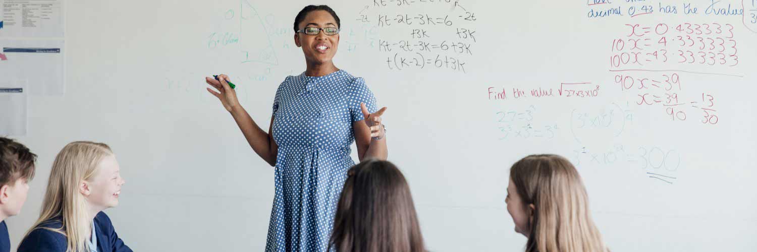 Female teacher in polka dot dress addressing young adults