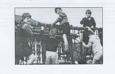 An old black and white photo of a group of children playing on a rope climbing frame