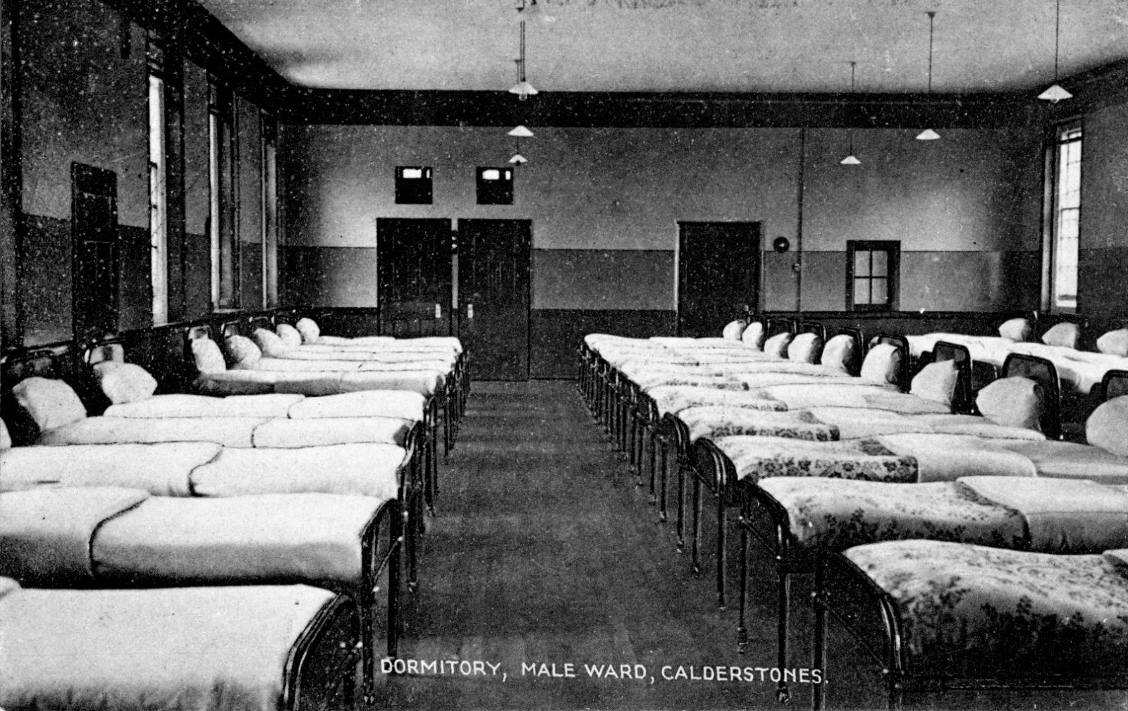 An old black and white photo showing lines of beds in a dorminary