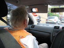 The rear view of a man sitting in the passenger seat of a car