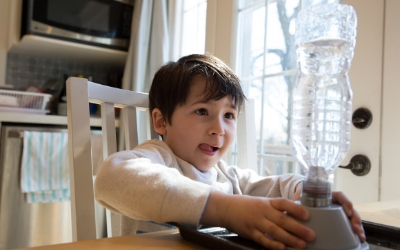 Boy making tornado in water bottle in kitchen