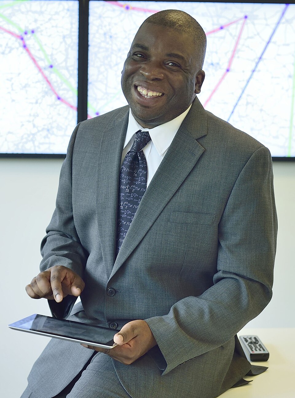 Nira Chamberlain sitting on a desk holding an ipad.