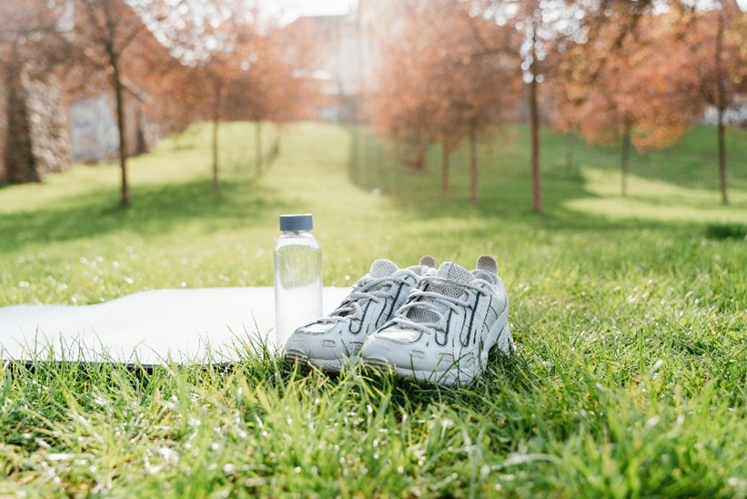 A photo of a pair of trainers on some grass next to a plastic water bottle