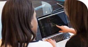 Two people looking at coding on a laptop.
