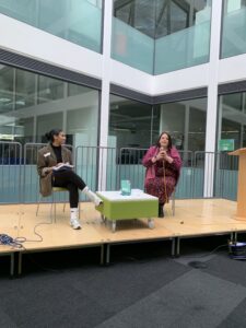 A middle-aged white woman is interviewed on stage by a young black woman. 