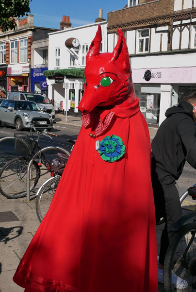 A morris dancer in red cloak and red animal mask