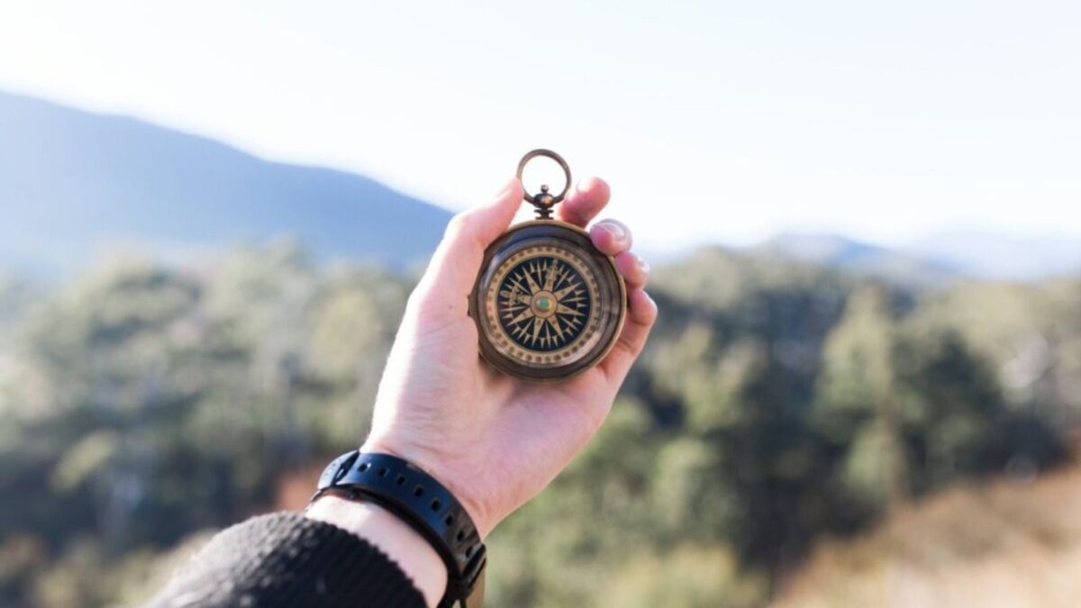 Compass held up against mountainous landscape