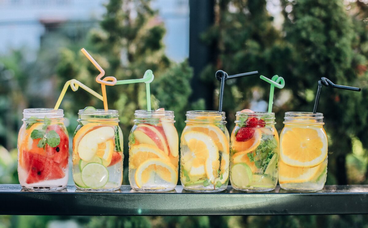 Six jars of lemonade on a table in a garden