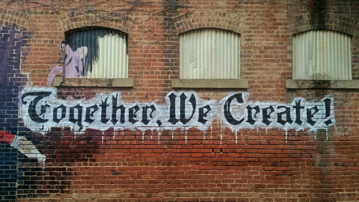 Grafitti spray painted on a wall. It says 'Together we create'.