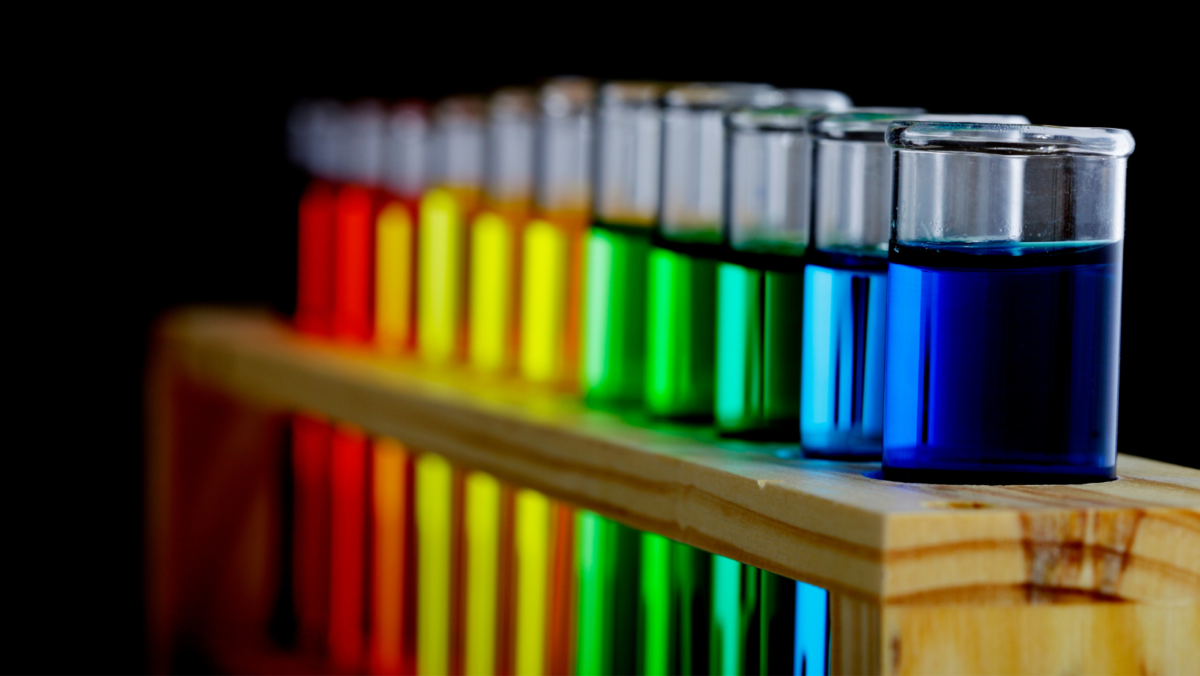 Photo of a rack of test tubes. Each tube has a different colour of the rainbow spectrum.