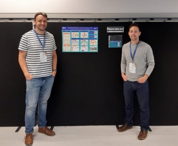 A photo of Paul and James standing next to the poster that was created by the OU LD Sustainabilty team for the EDEN conference.