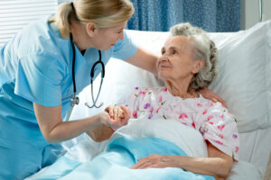 Photo of nurse caring for elderly lady in hospital bed