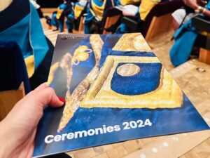 Woman's hand with red painted nails hold the programme from her OU graduation ceremony.