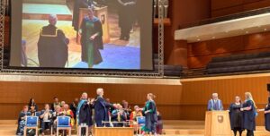 Image of a woman crossing the stage to collect her certificate at her graduation ceremony.