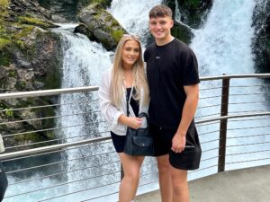 Young couple stood in front of a waterfall.