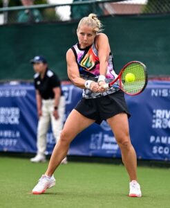 Alice on court hitting a backhand