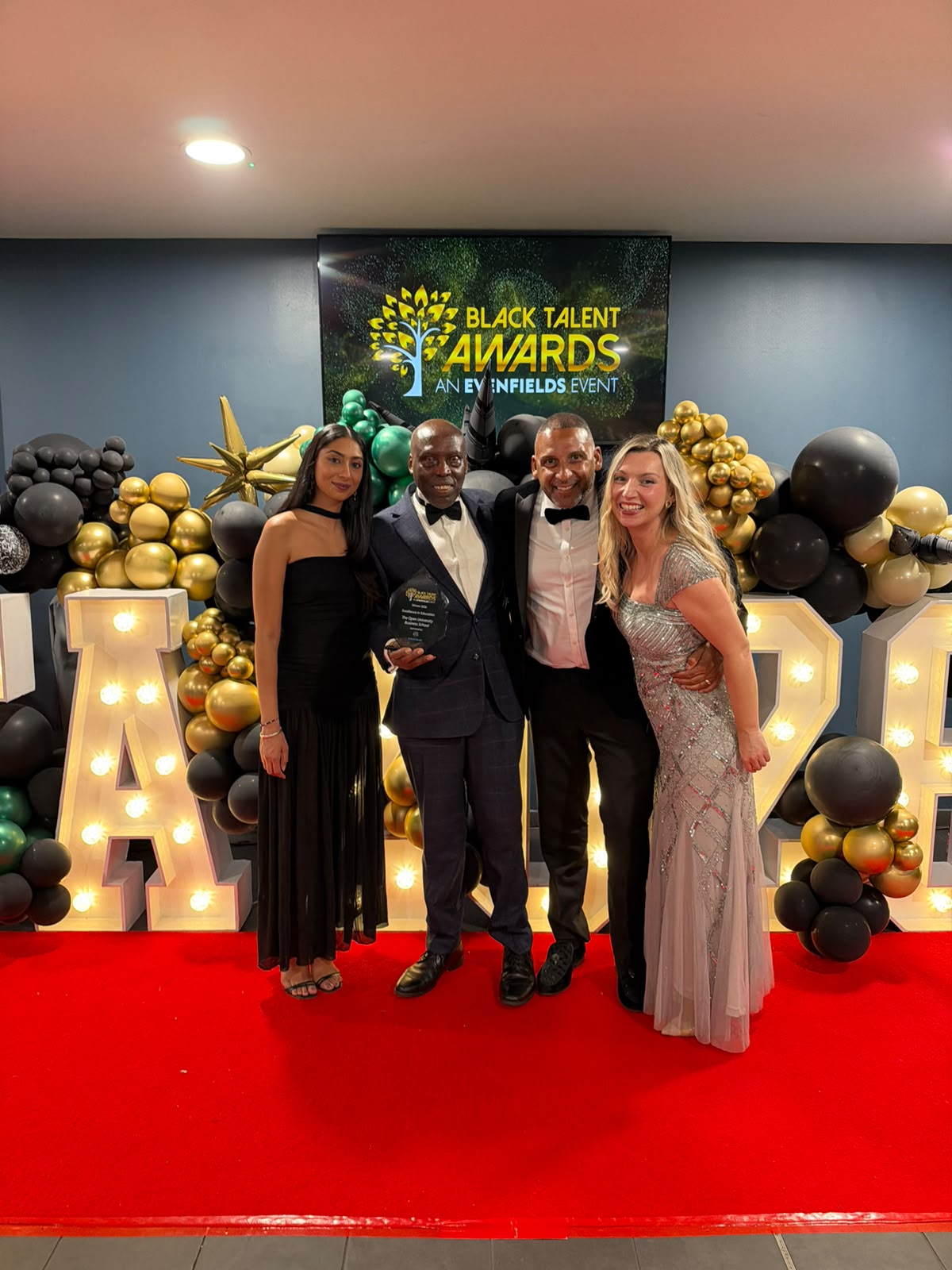 Members of the winning OU team and partner organisations standing in front of a Black Talent Awards banner.
