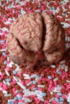 A model of a brain, laying on a pile of medicinal tablets.