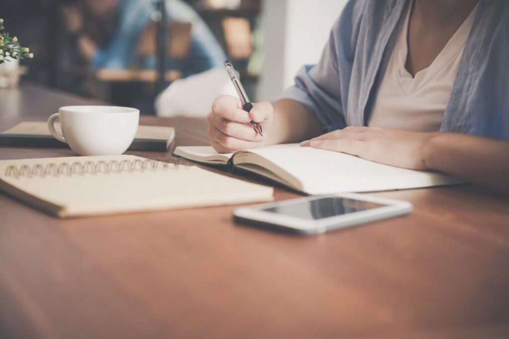 Woman Writing on a Notebook Beside Teacup and Tablet Computer · Free Stock Photo (pexels.com)