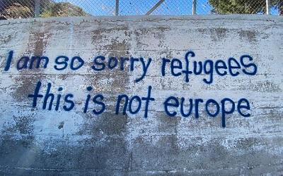 A wall with grafitti reads "I am so sorry refugees this is not Europe"