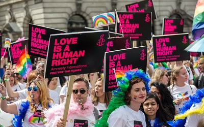 A LGBTQ protest shows protestors with signs that say "Love is a human right"