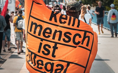 A flag at a protest reads "Kein mensch isnt illegal" which translates to English as "no one is illegal"