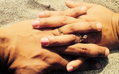 Two hands hold each other on a beach