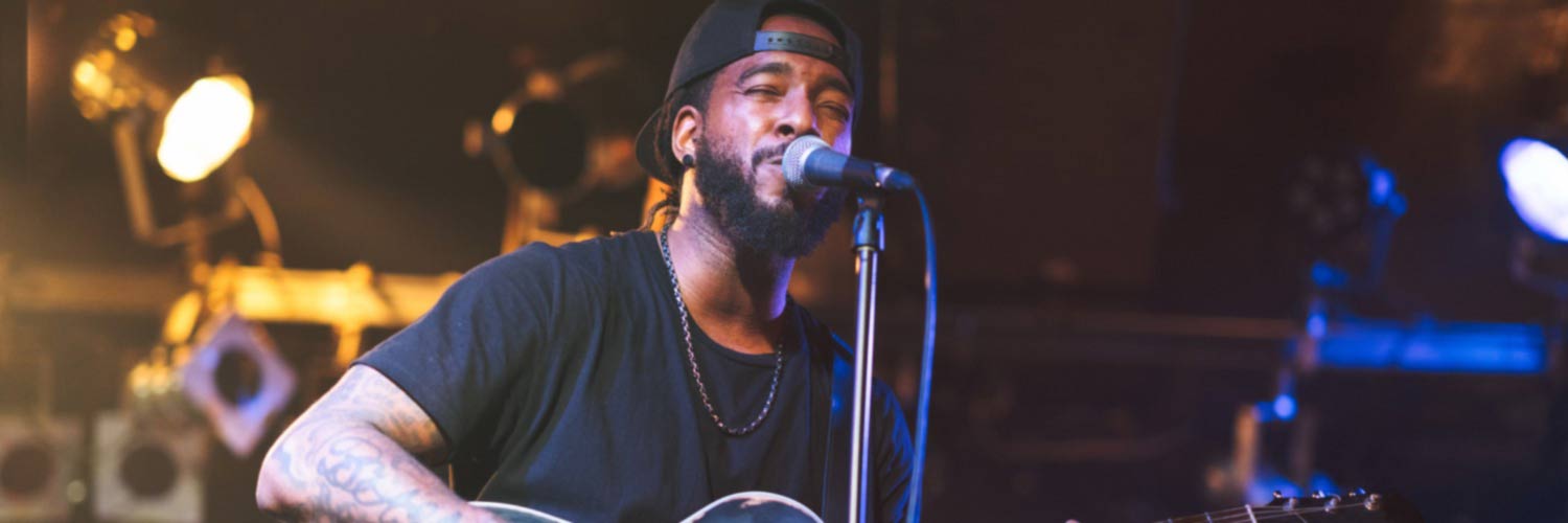 Man at microphone singing and playing guitar