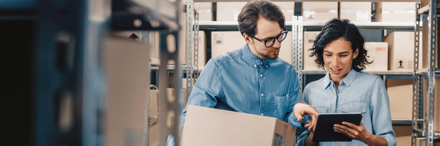 Two colleagues checking a tablet computer in a warehouse