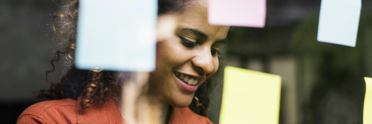 Smiling worker studies a wall of sticky notes