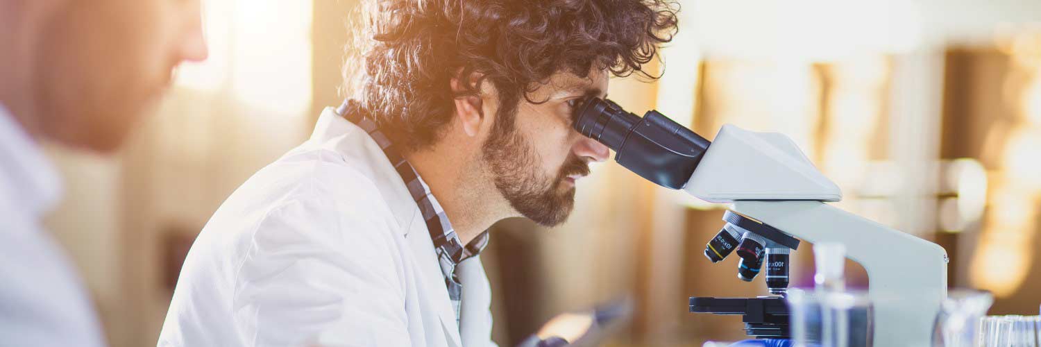 Male student using microscope