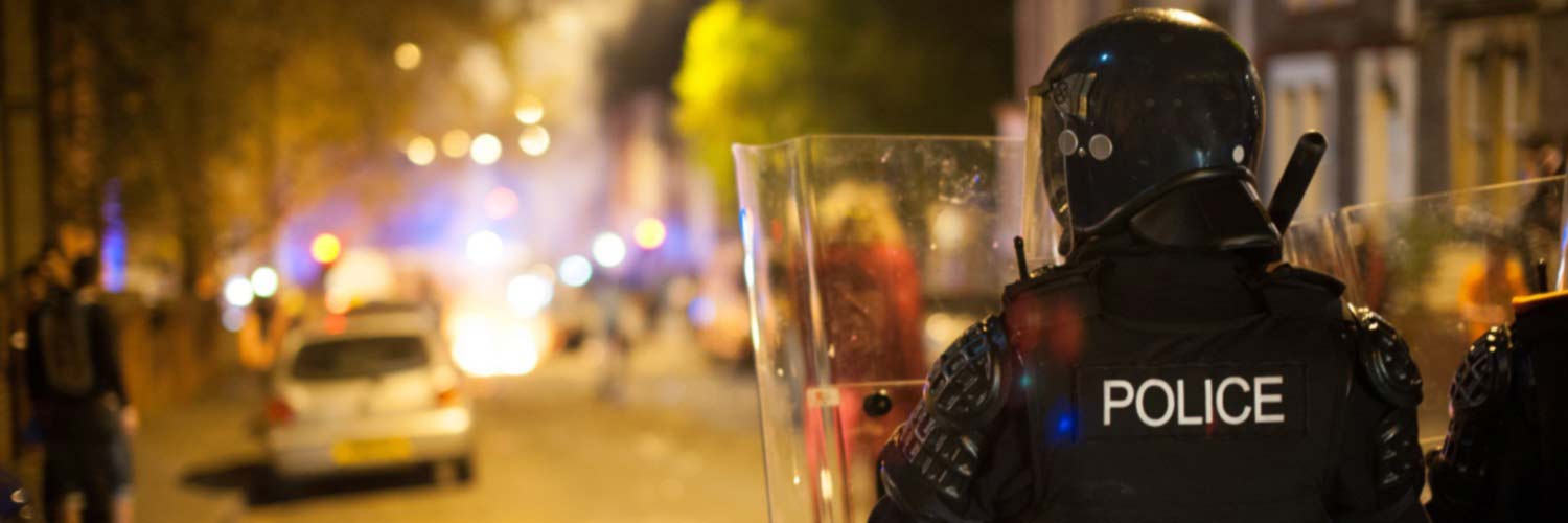 Back view of two police officers with riot shields in the street