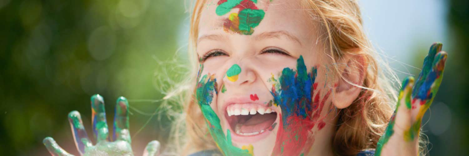 Smiling little girl with paint covered hands and face