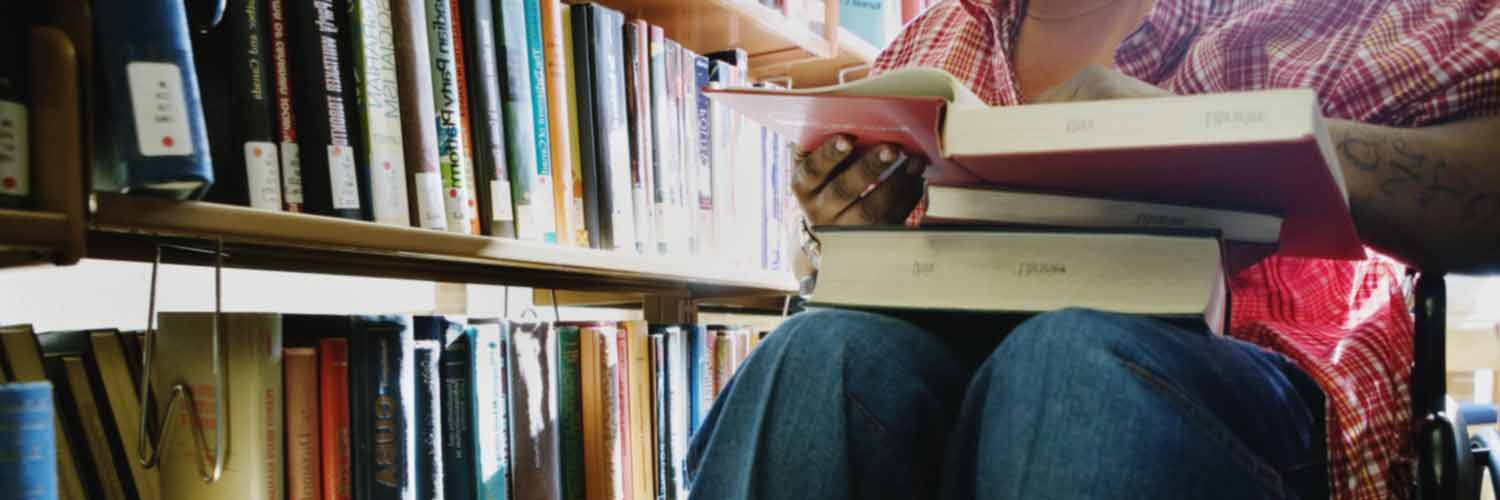 Student in a wheelchair choosing books in a library