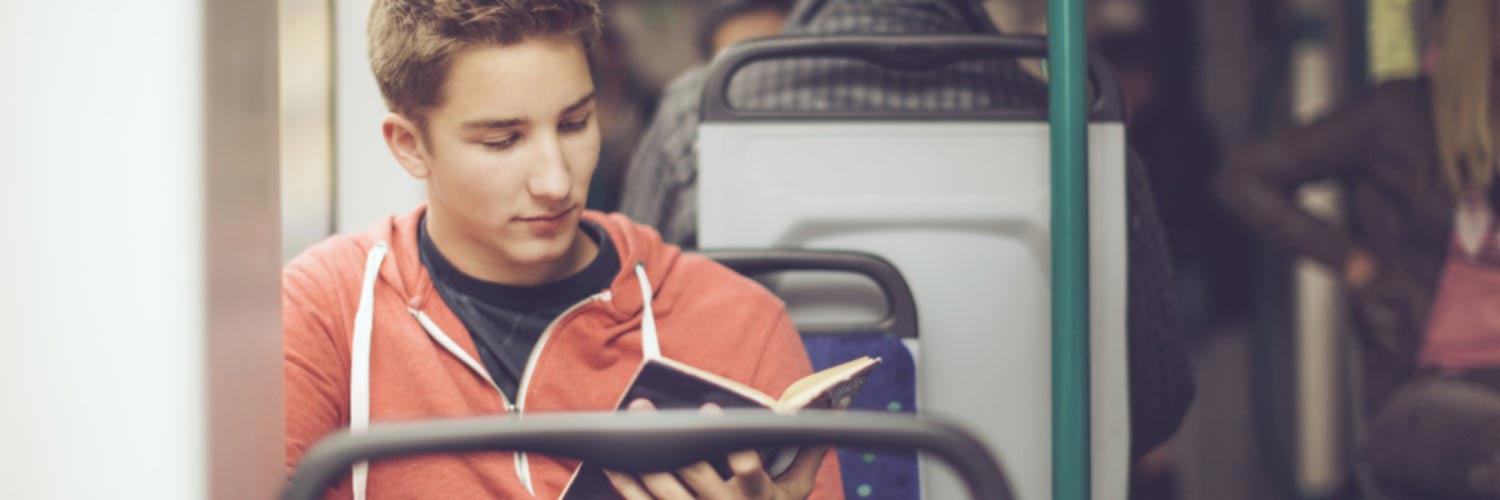 Young man reading a book on a bus