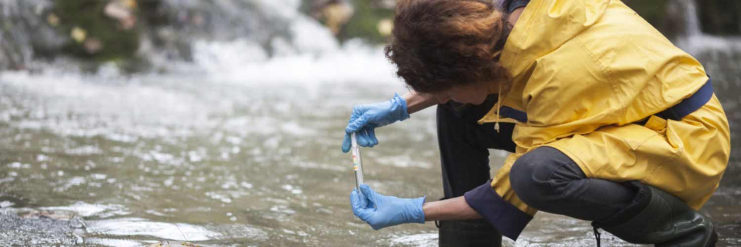 Student or professional taking water sample from a river