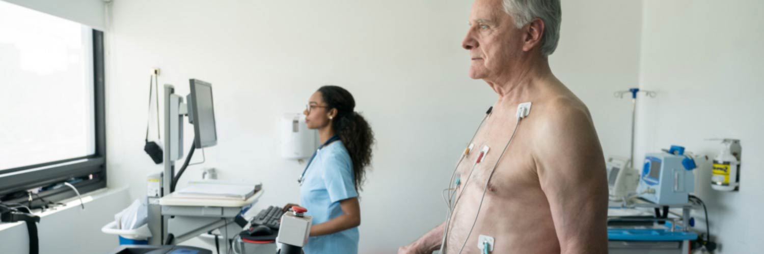 Healthcare worker examining monitor during cardiac scan on older patient