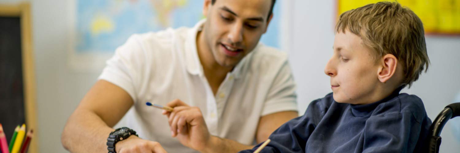 Care worker assisting in painting with a child in a wheelchair