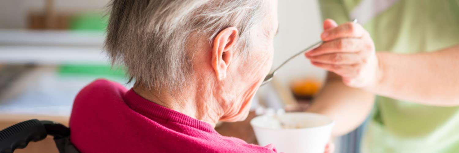 Healthcare worker helping to feed an elderly patient