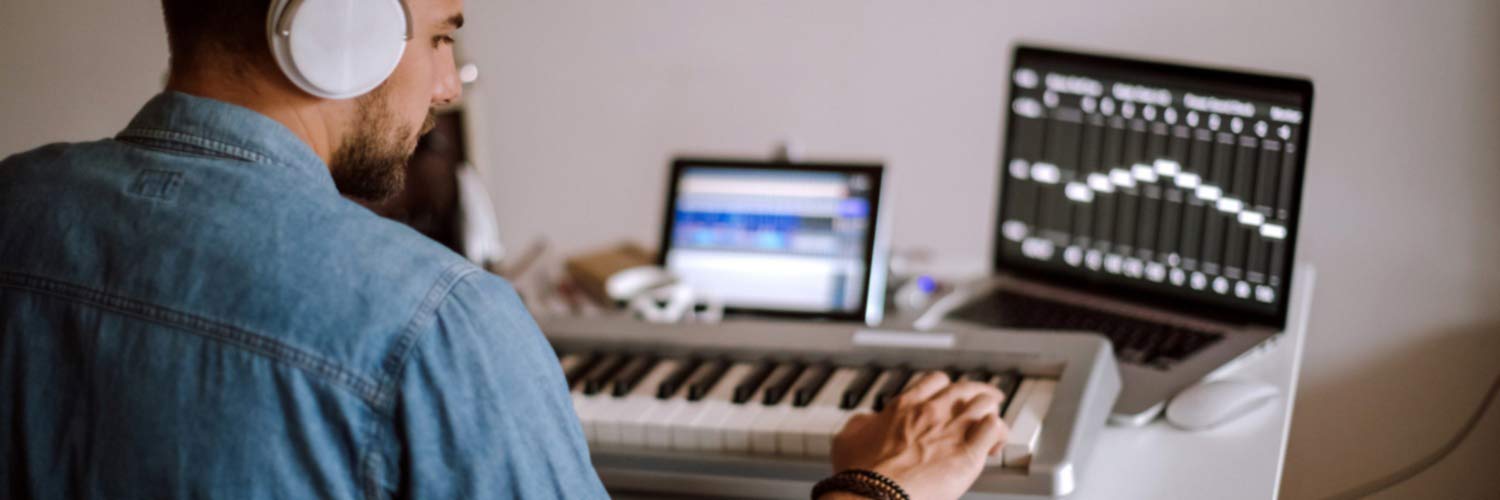 Man composing music with keyboard and laptop