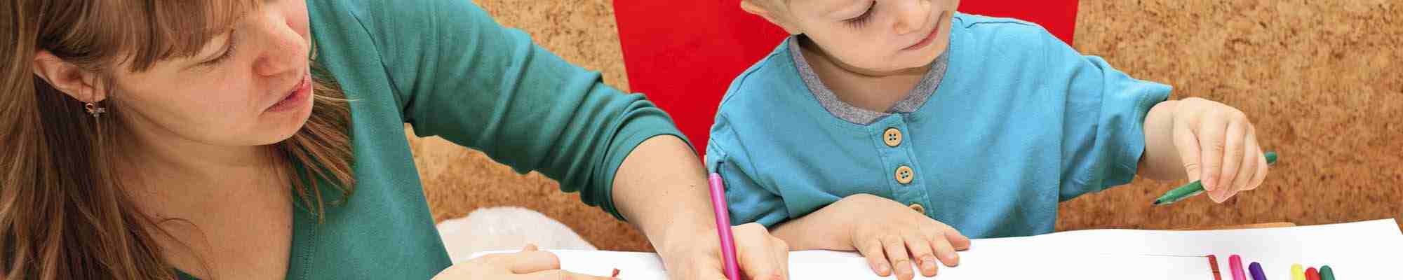 Child with teacher drawing in play room photo