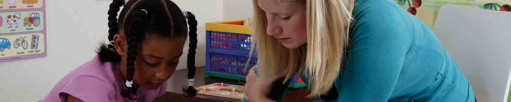 Teaching assistant working with primary school child photo