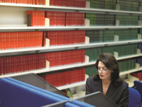 woman at computer with books behind