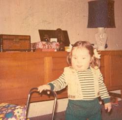 An old colour photo of a small child in a living room