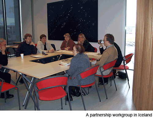 A group of people sitting round tables in a small meeting room