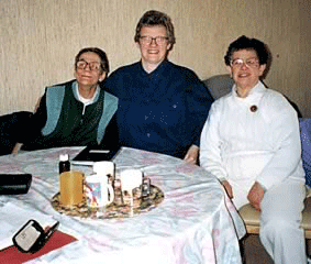 Gloria, Mabel and another person sitting round a table smiling
