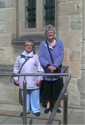Mabel Cooper and Gloria Ferris standing outside an historic building