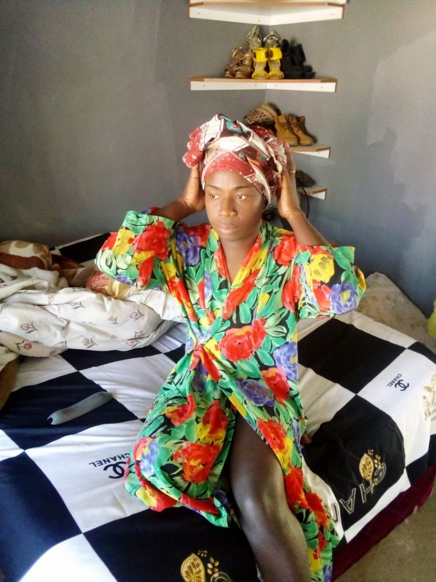 Photo shows a trans woman in Mozambique at home on her bed